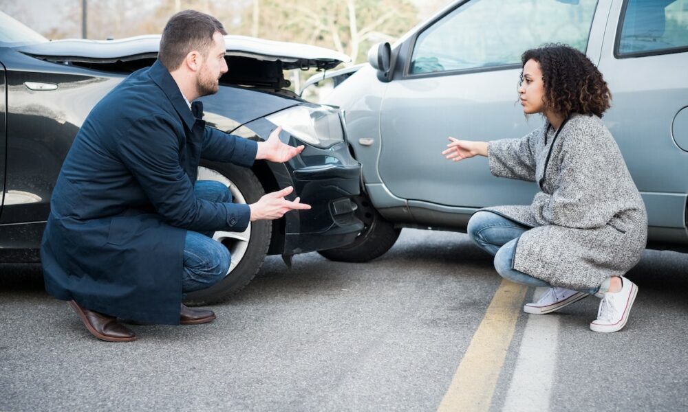 Man and woman arguing after bad car crash